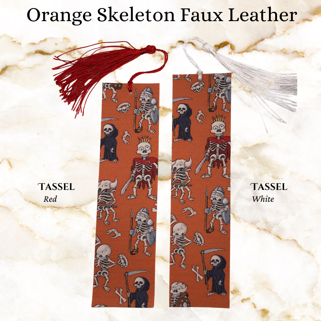 skeletons in clothes on orange faux leather book mark - 1 in red tassel and 1 with a while tassel -
