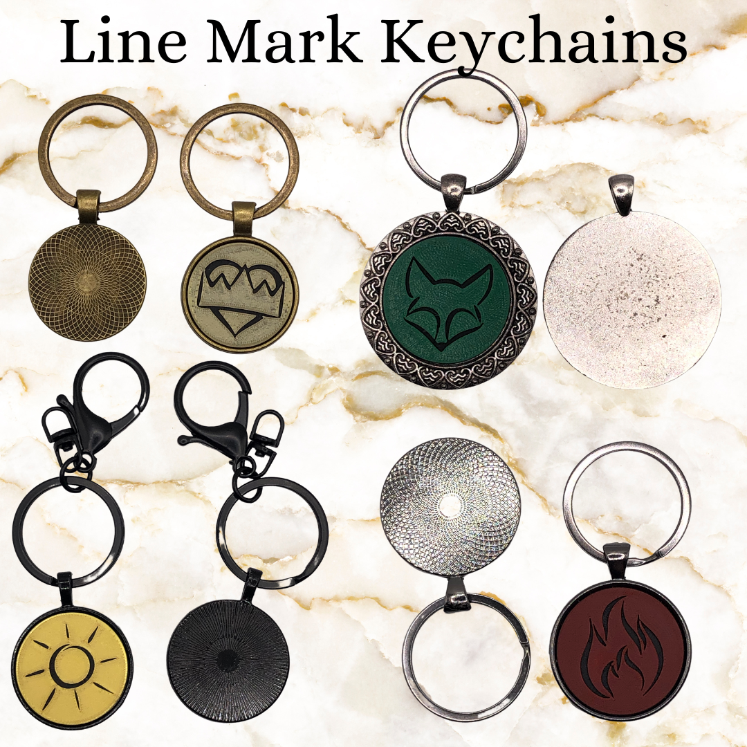 Image showing front and back of 4 keychains - brass (smaller size), extra large silver with heart pattern around the outside, black with a hook on the key ring, and dark chrome